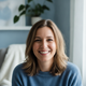 A candid portrait headshot of a smiling woman in her late 30s, exuding trust and satisfaction against a blurred background.
